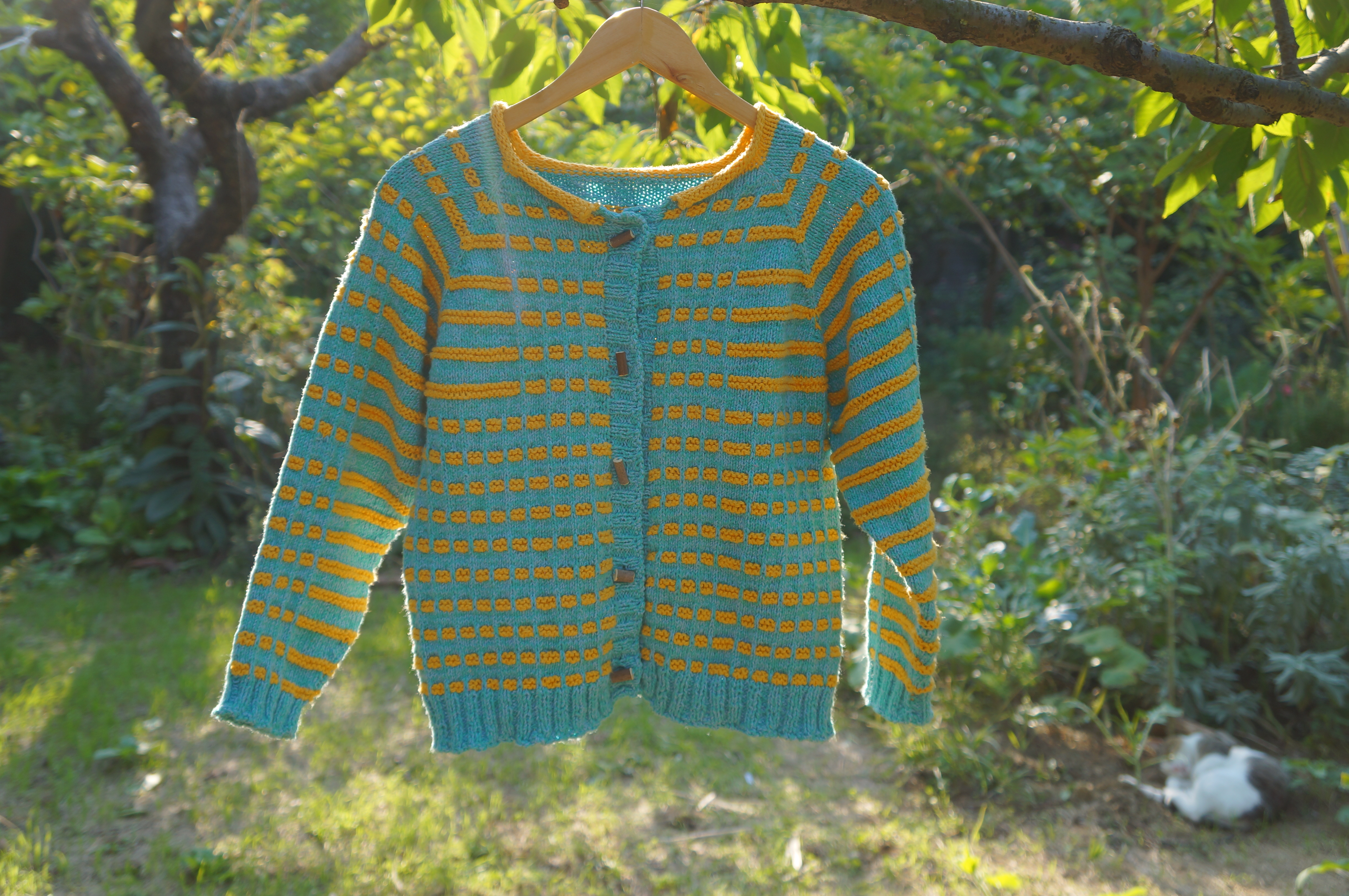 Top down hand knitted raglan sleeve cardigan with cotton yarns and handmade fig wood buttons